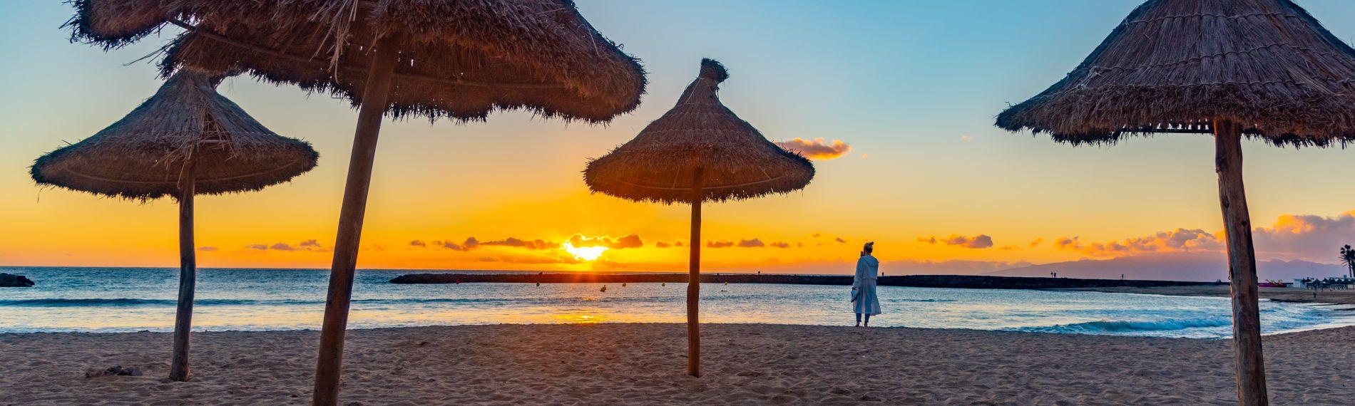 Woman photographing the sunset over the sea at Playa del Camison in popular Playa de las Americas, one of Tenerife's best beaches